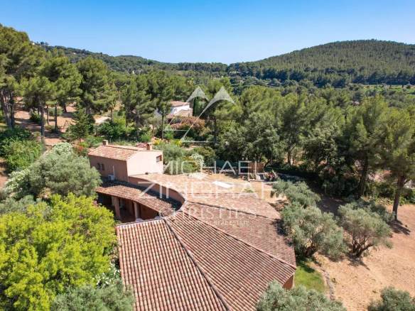Aerial view of a terracotta-roof villa surrounded by pine trees in a sunny countryside setting