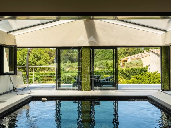 Intérieur d'une villa contemporaine avec piscine et grandes baies vitrées donnant sur la nature.