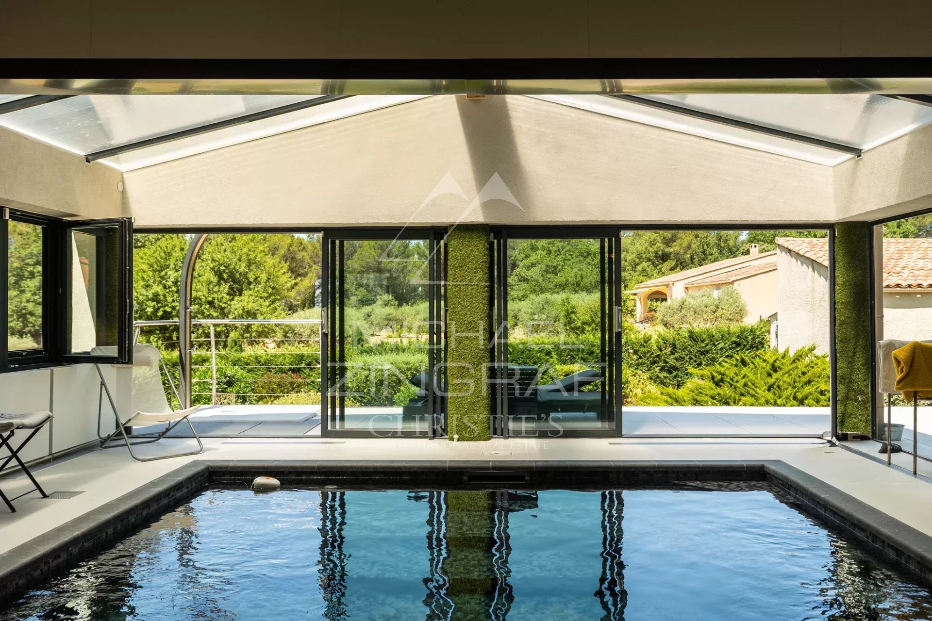 Intérieur d'une villa contemporaine avec piscine et grandes baies vitrées donnant sur la nature.
