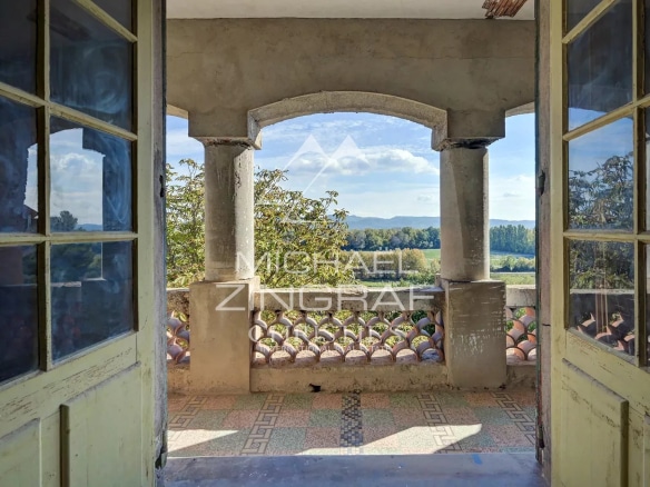 Vue depuis un balcon avec colonnes, offrant un panorama sur la nature environnante.