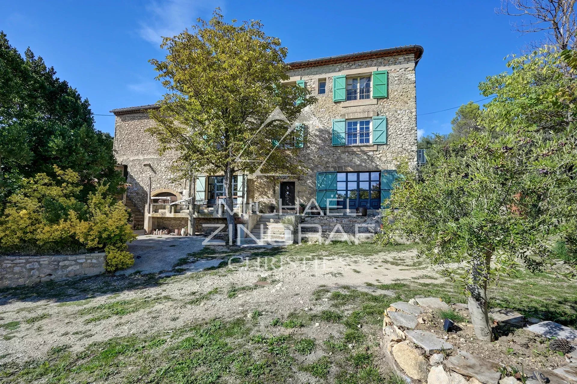 Propriété en pierre avec fenêtres colorées et jardin, située dans le Sud du Luberon.