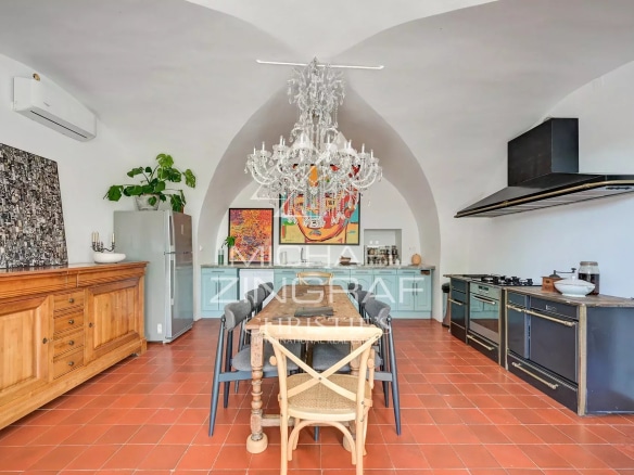 Cuisine d'une propriété d'exception avec un grand lustre et des meubles en bois dans un cadre lumineux.