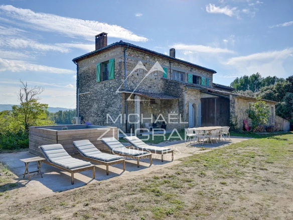 Maison en pierre avec terrasse et transats, située dans un paysage naturel du Sud du Luberon.