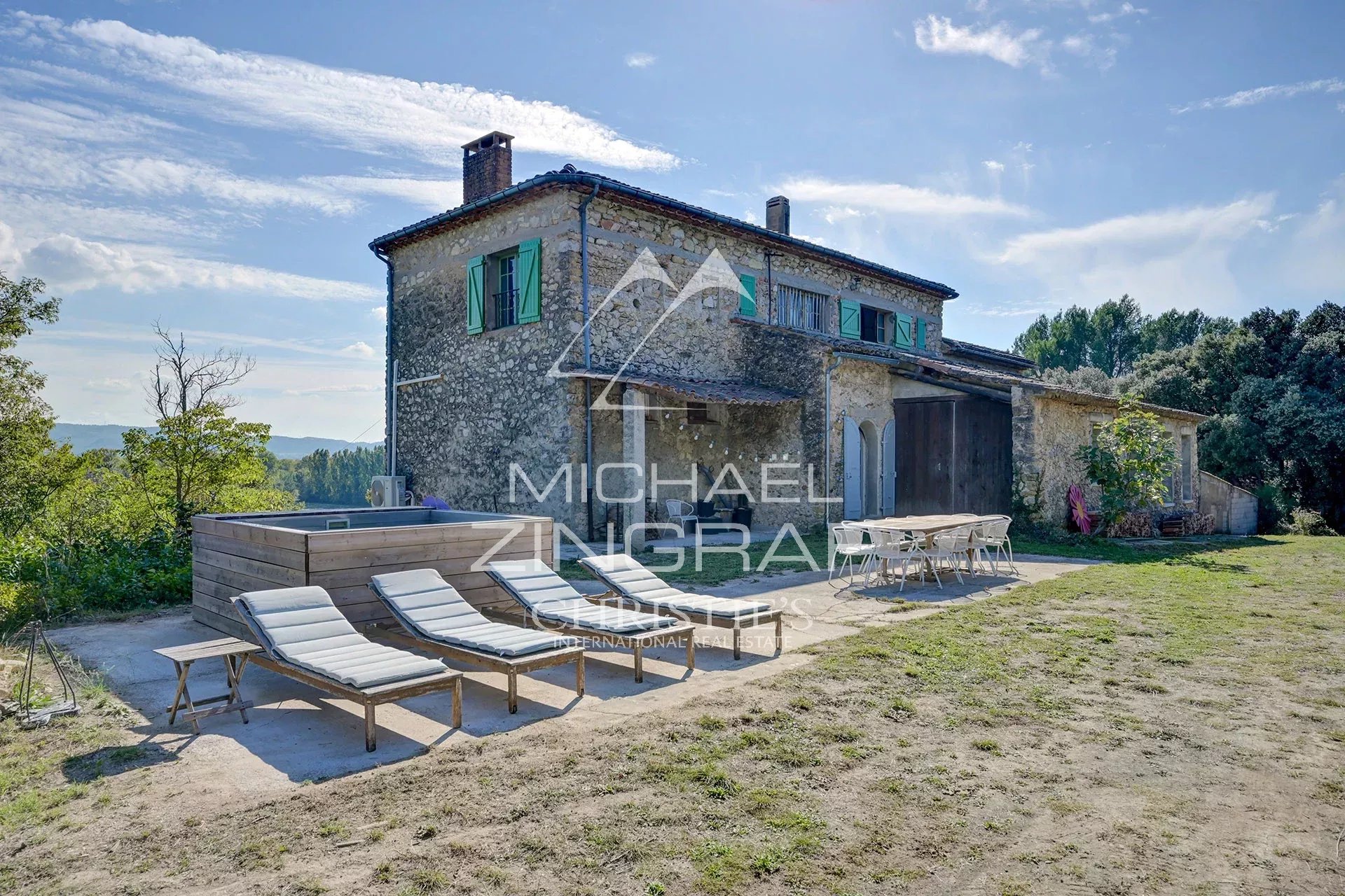 Maison en pierre avec terrasse et transats, située dans un paysage naturel du Sud du Luberon.