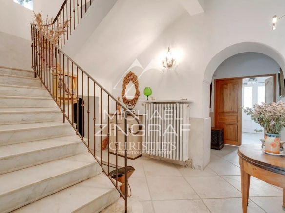 Escalier en marbre dans une demeure du XIXe siècle avec un hall d'entrée lumineux.