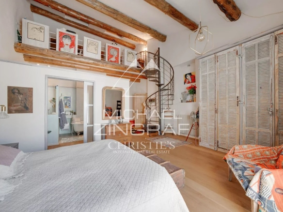 Intérieur d'une maison du XIXe siècle avec des poutres apparentes et un escalier en colimaçon.
