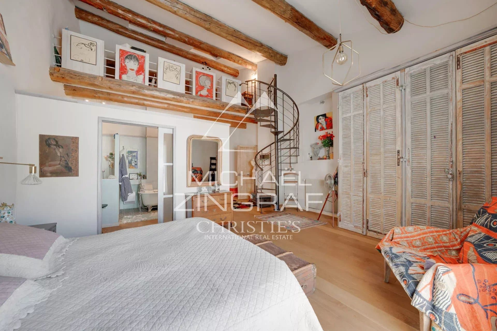 Intérieur d'une maison du XIXe siècle avec des poutres apparentes et un escalier en colimaçon.