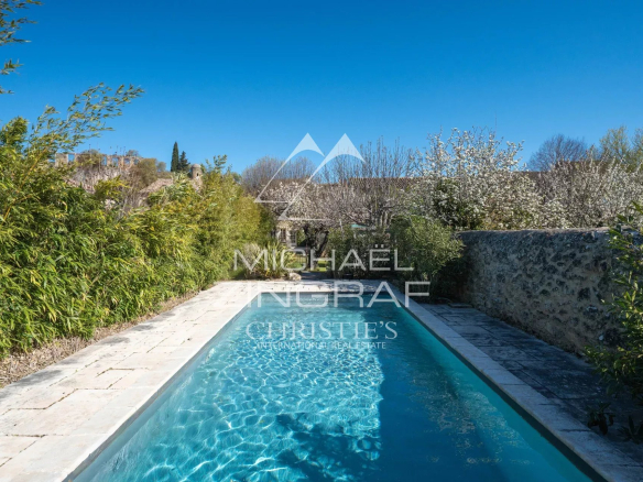 Piscine extérieure d'une demeure provençale avec végétation environnante.