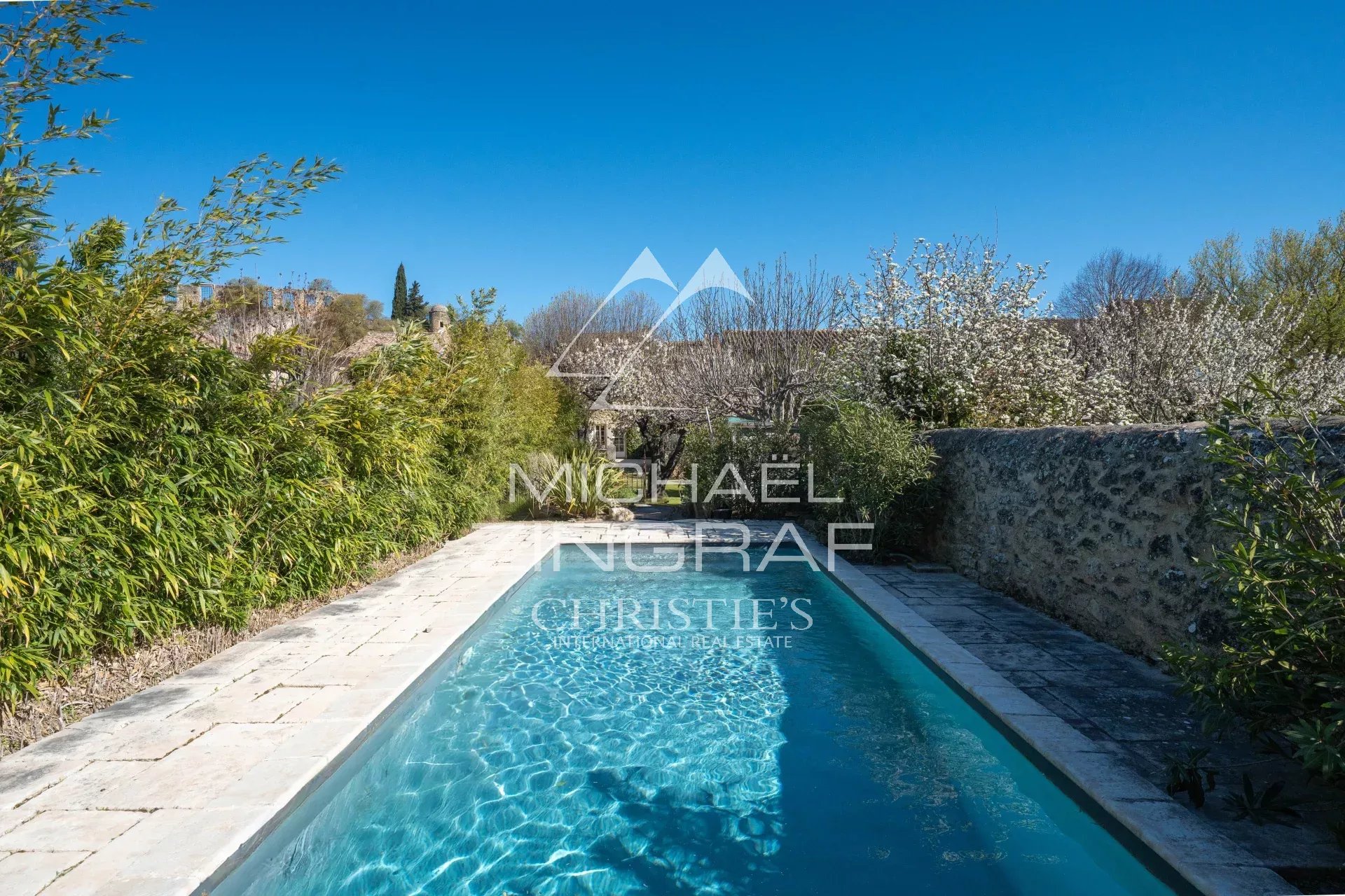 Piscine extérieure d'une demeure provençale avec végétation environnante.