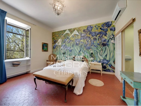 Room in a Provençal estate with a large wall decorated with flowers, windows open onto nature.