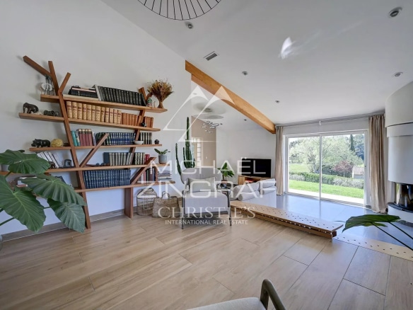 Interior of a bright house with wooden shelves and a view of the garden.