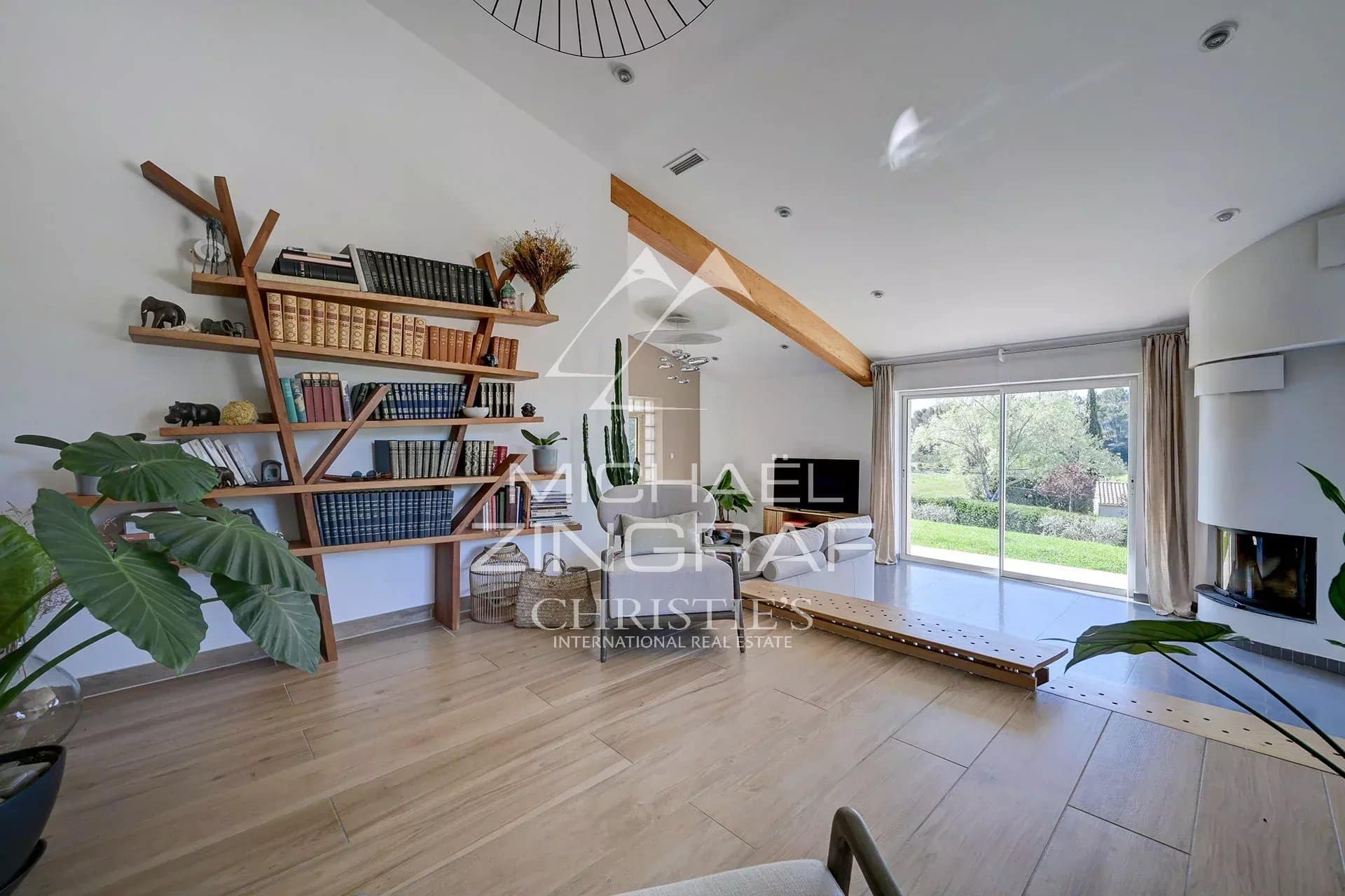 Interior of a bright house with wooden shelves and a view of the garden.