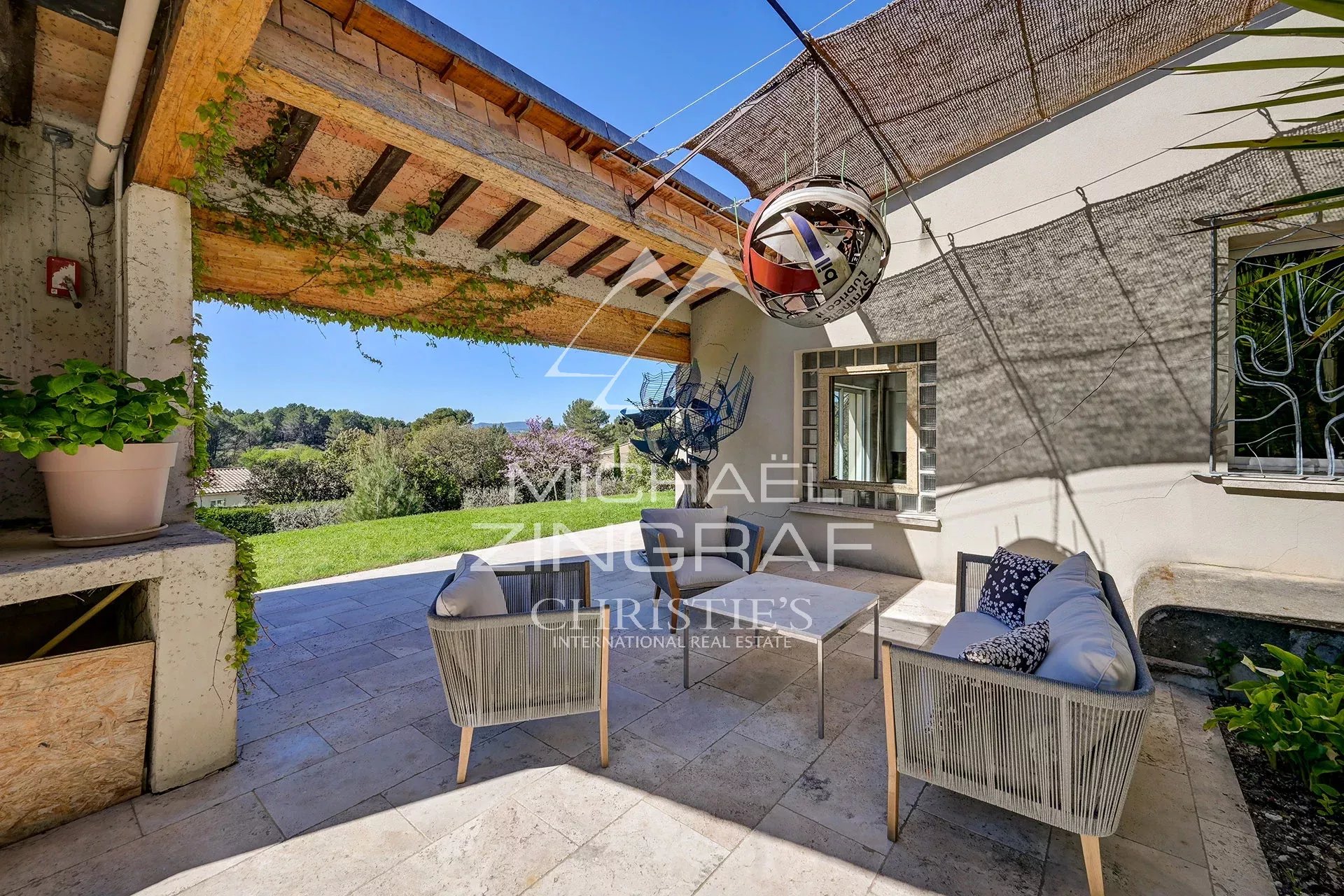 Terrace of a bright property in Mérindol with outdoor furniture and views of nature.