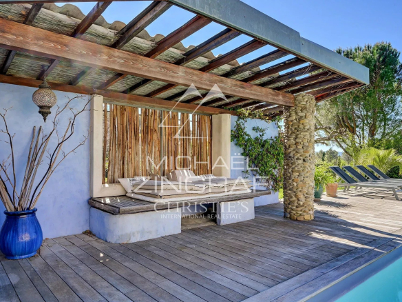 Wooden terrace with lounge area and swimming pool, surrounded by greenery in Mérindol.
