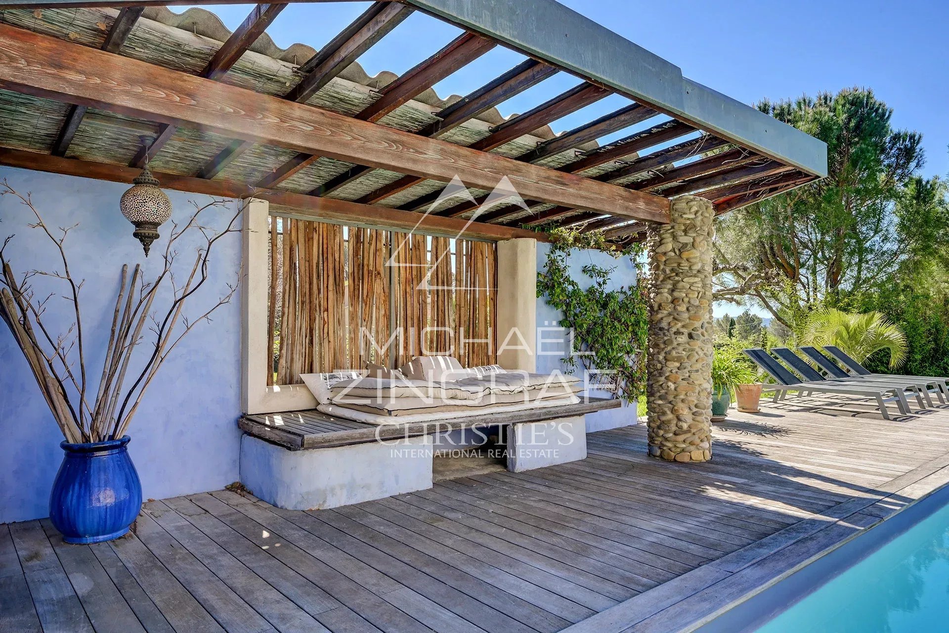 Wooden terrace with lounge area and swimming pool, surrounded by greenery in Mérindol.