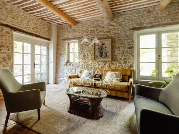 Intérieur d'une magnanerie rénovée avec murs en pierre et mobilier moderne.