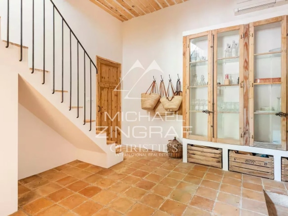 Intérieur d'une magnanerie rénovée avec un escalier et des étagères en bois.