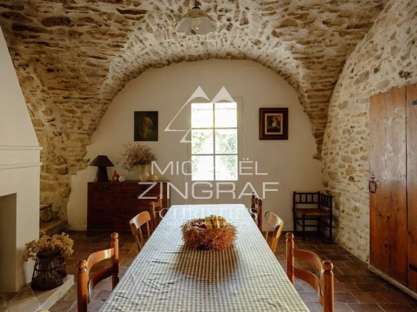 Intérieur d'une magnanerie rénovée avec des murs en pierre et une table en bois