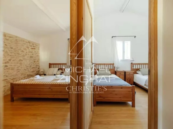 Chambre d'une magnanerie rénovée avec lits en bois et murs en pierre apparente.