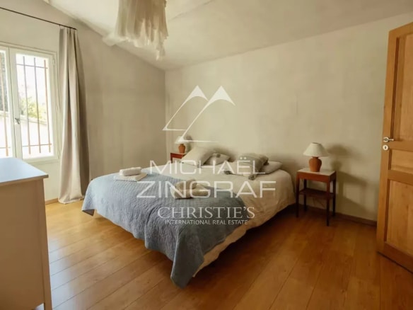 Chambre d'une magnanerie rénovée avec lit double et fenêtres lumineuses.