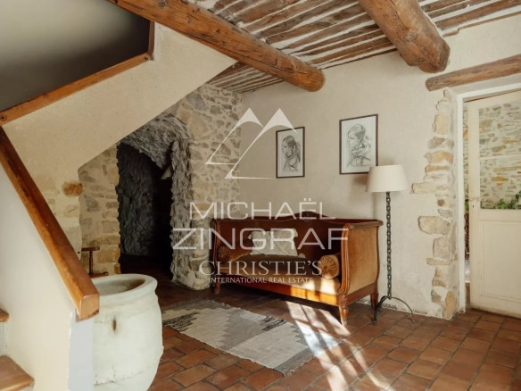 Intérieur d'une magnanerie rénovée avec des murs en pierre et un escalier en bois.