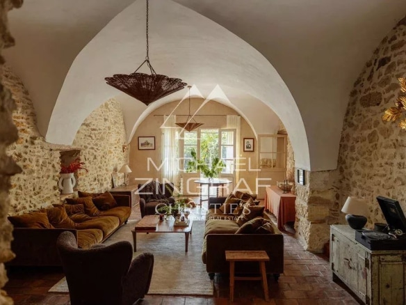 Intérieur d'une magnanerie rénovée avec un salon spacieux et des murs en pierre apparente.