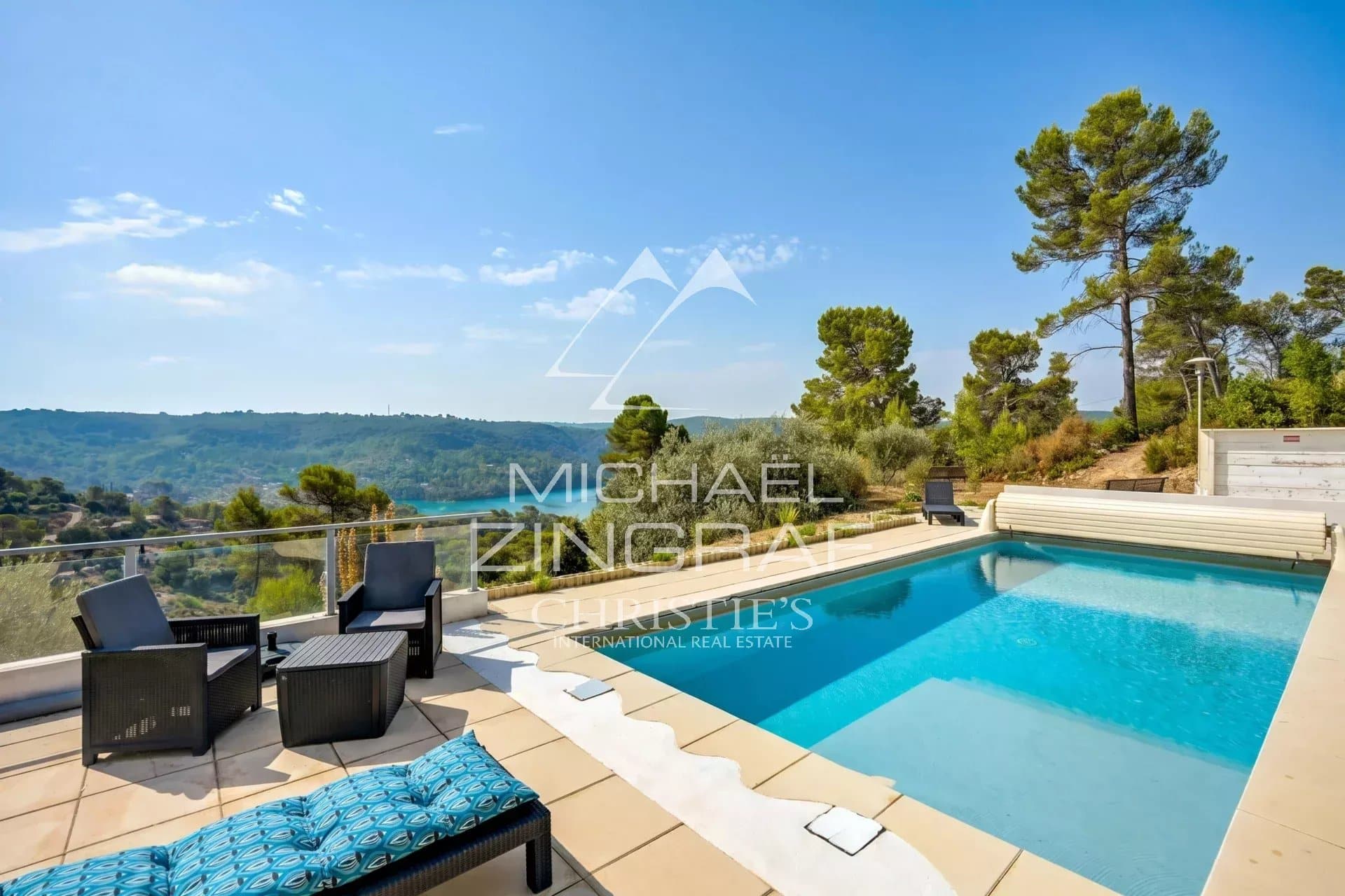 Panoramic view of Lake Esparron with swimming pool and green landscape in the background.