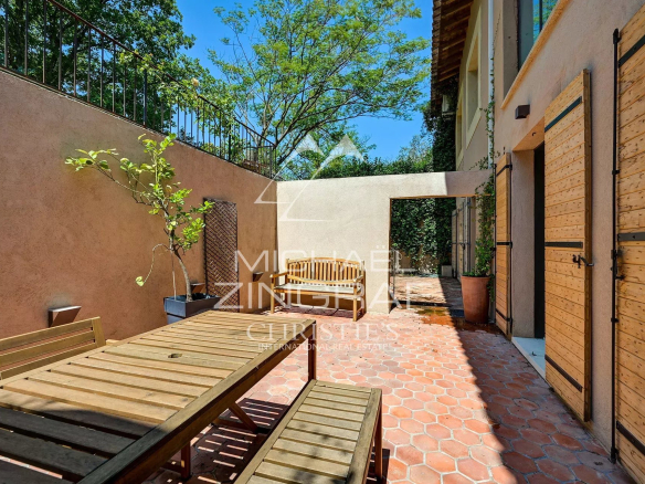 Wooden terrace with table, surrounded by greenery in a property in Aix-en-Provence.