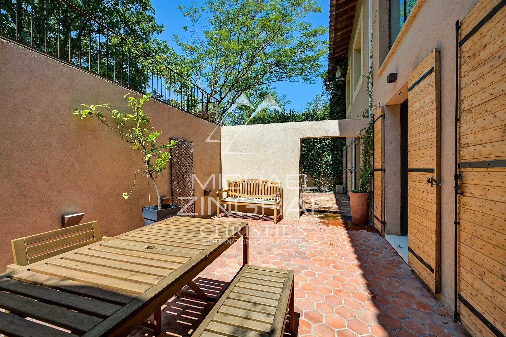 Wooden terrace with table, surrounded by greenery in a property in Aix-en-Provence.