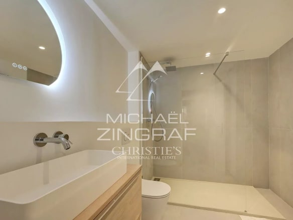 Modern bathroom with shower and sink, light walls and integrated lighting.