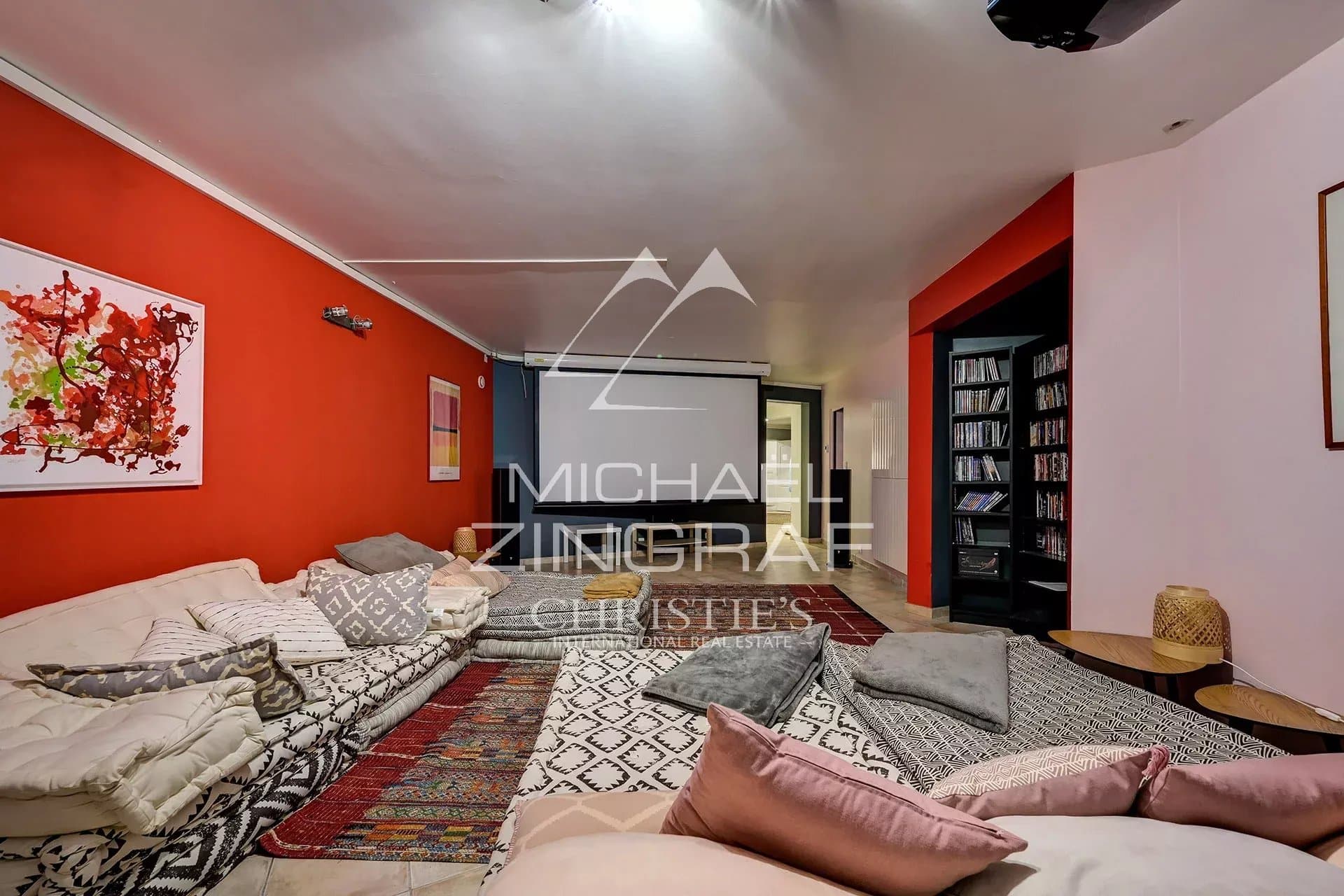 Spacious living room with red walls and rug, comfortable furniture, soft lighting.