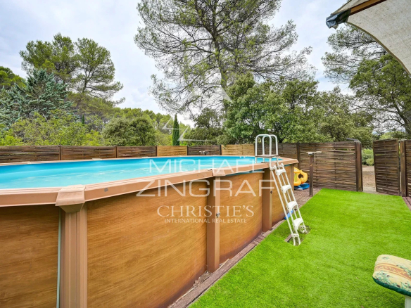 Above-ground swimming pool surrounded by wooden terraces and greenery in a family home in Fuveau.