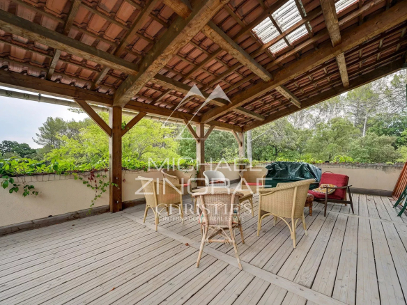 Wooden terrace with furniture, surrounded by greenery in a family home in Fuveau.