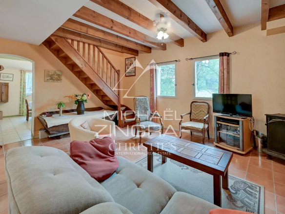Intérieur d'une maison familiale avec salon, cheminée et escaliers en bois.