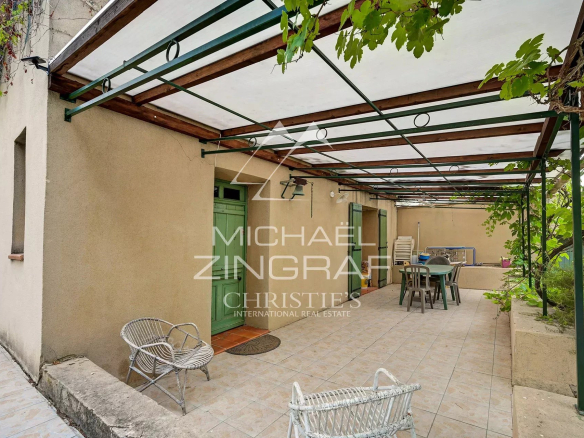 Terrasse couverte d'une maison familiale à Fuveau, entourée de verdure et d'oliviers.
