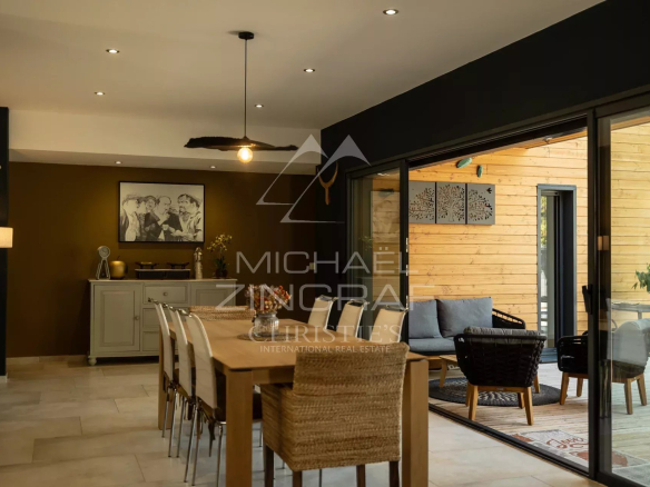 Interior of a contemporary house with dining room and access to a wooden terrace.