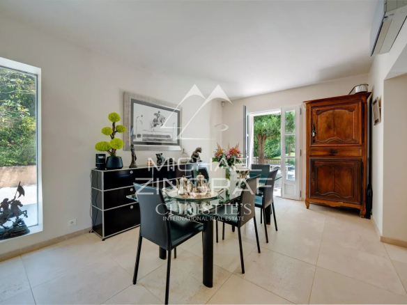 Dining room of an elegant property with access to a terrace, surrounded by greenery.