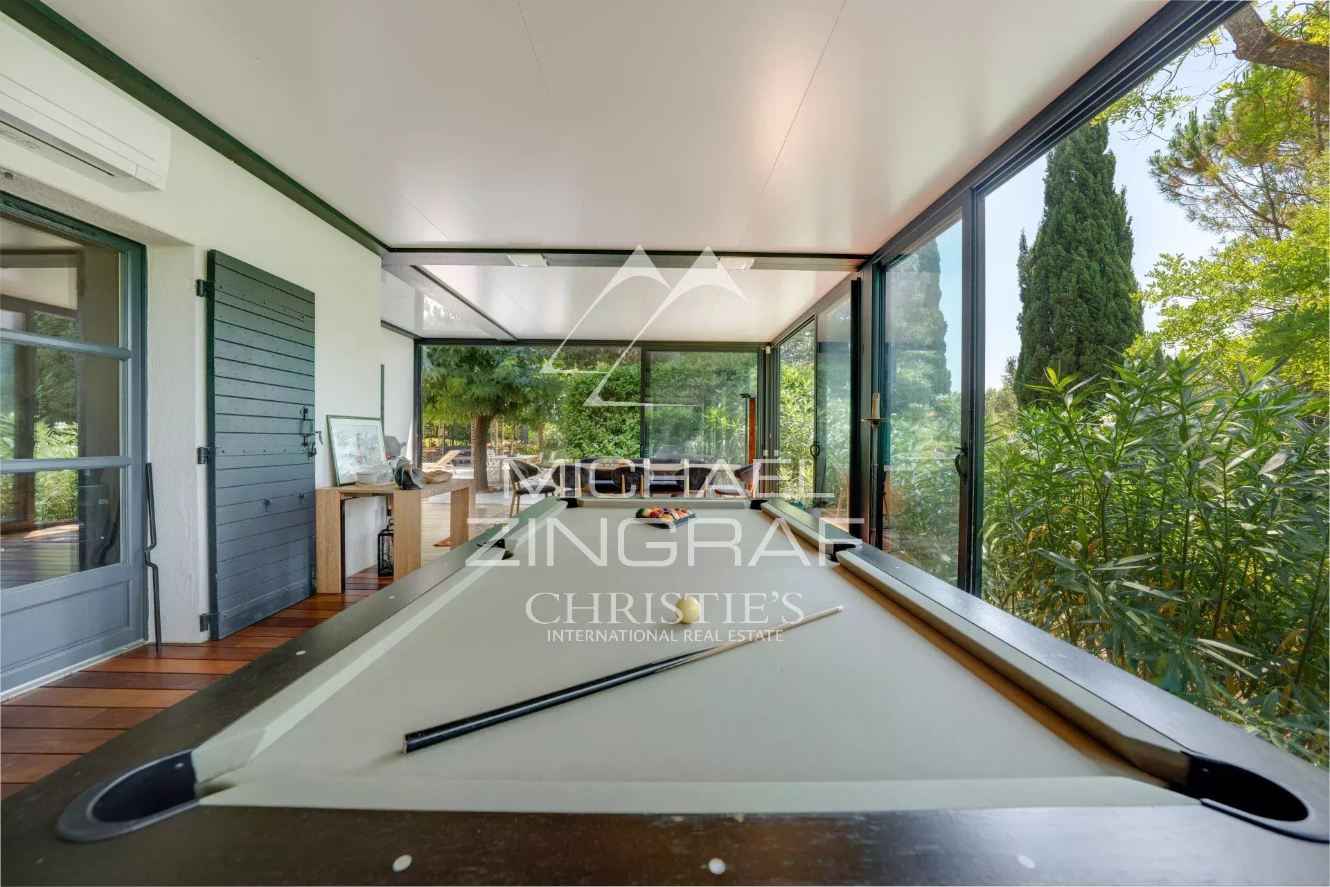 Interior of a property in Aix-en-Provence Interior of a property with a pool table, large bay windows and a view of the greenery.