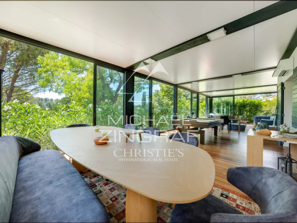 Interior of a property in Aix-en-Provence with a large table and windows overlooking greenery.
