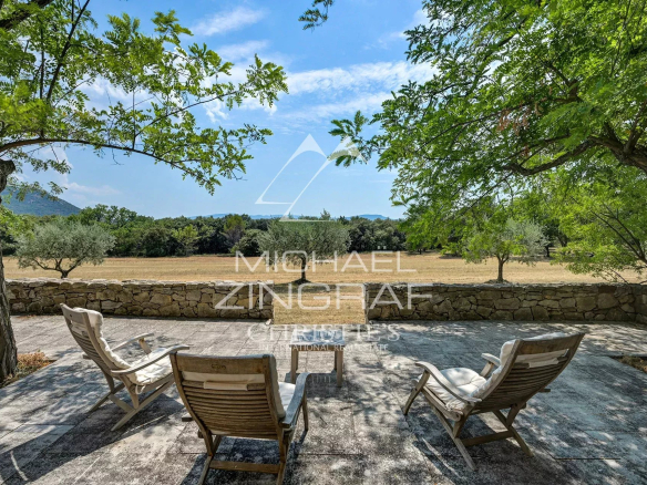 Terrace with sun loungers, overlooking a wooded estate and a clear sky.