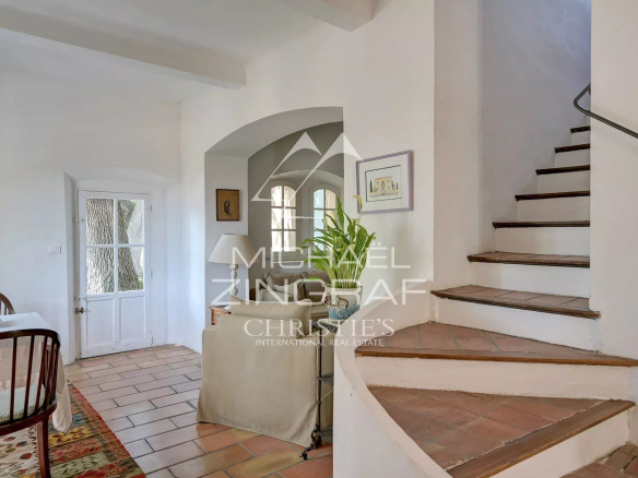 Interior of a Provençal country house with a staircase and a sitting area.