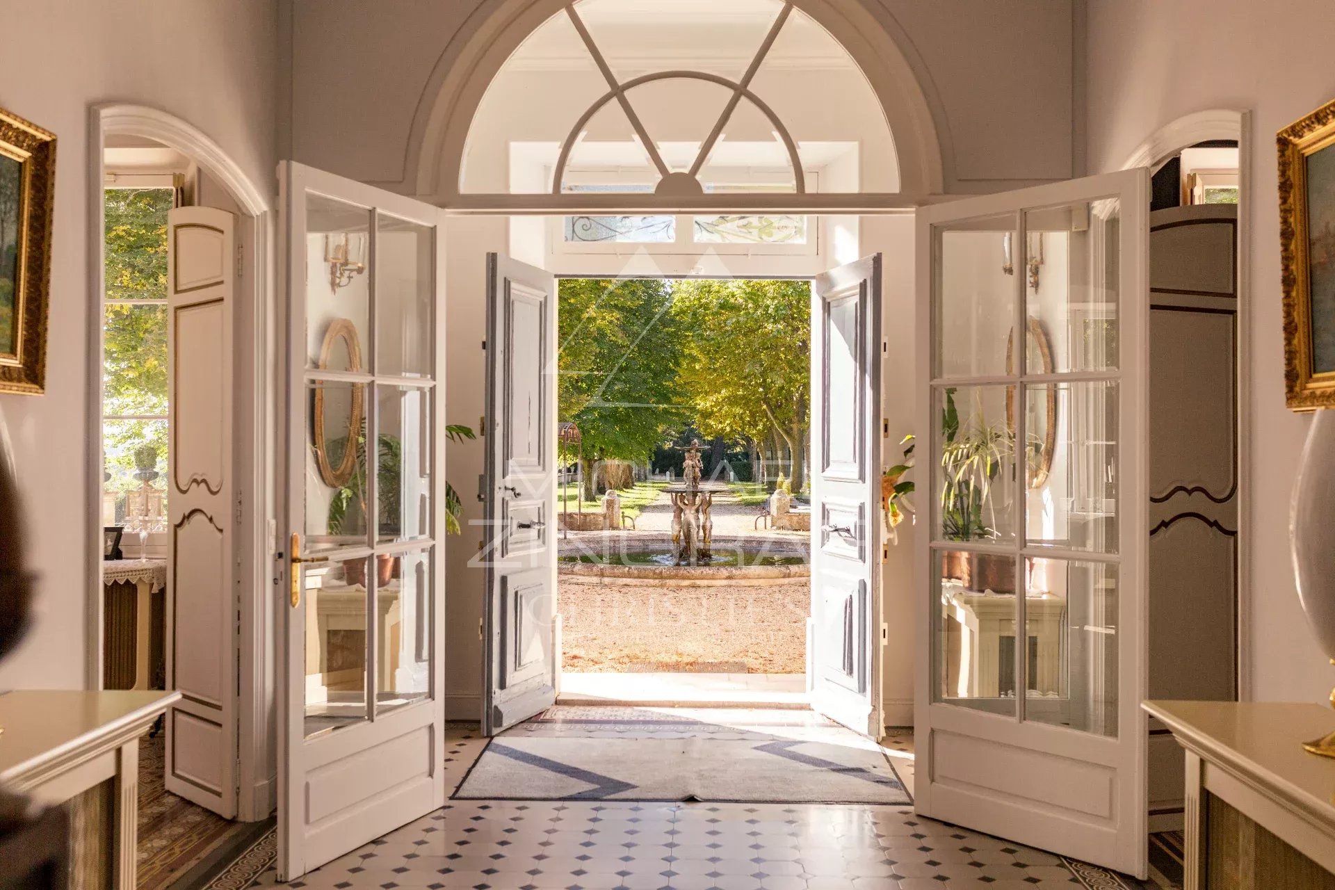 Propriété familiale à Aix-en-Provence Intérieur d'une propriété aixoise avec portes ouvertes sur un parc paysager.