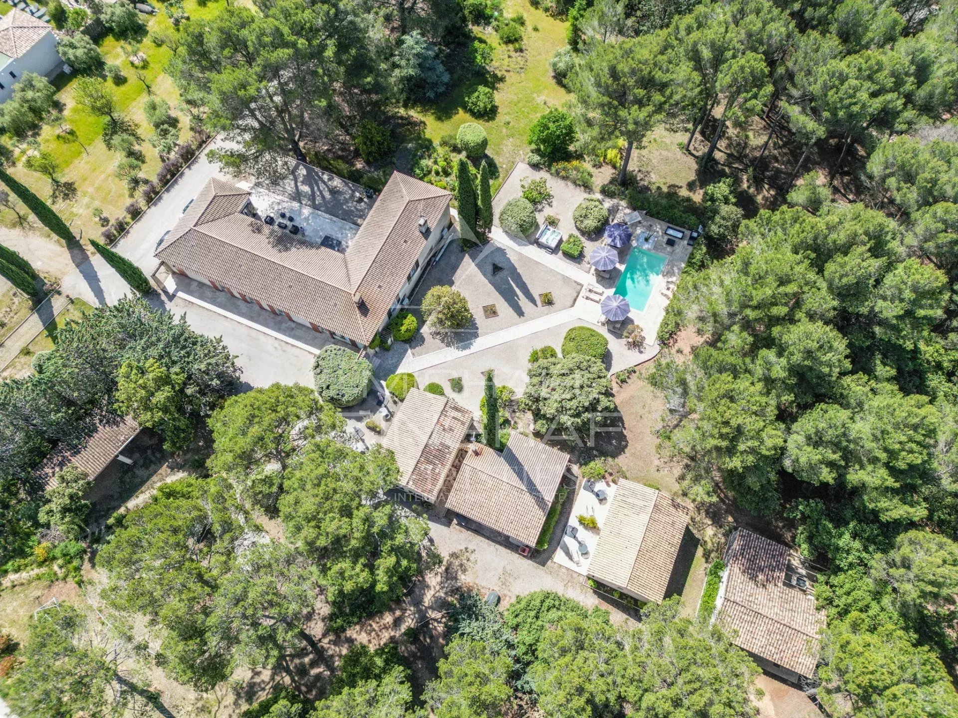 Propriété avec gîtes à Puget Vue aérienne d'une propriété avec plusieurs bâtiments et piscine, entourée d'arbres.