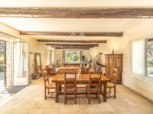 Intérieur d'une propriété rénovée avec une grande salle à manger et des poutres apparentes.