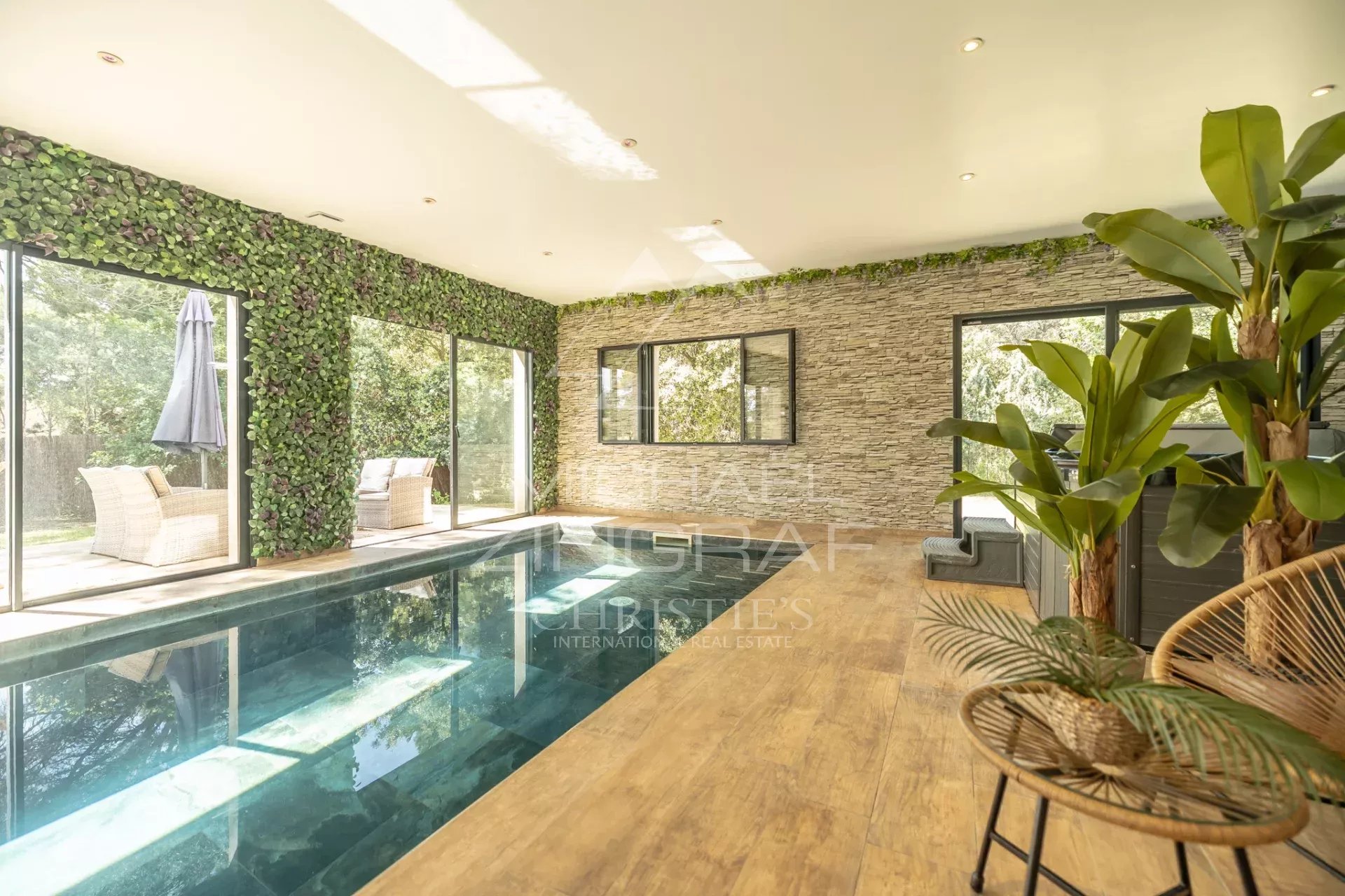 Intérieur d’une propriété avec piscine Intérieur d'une propriété avec piscine et grandes fenêtres, entouré de verdure.