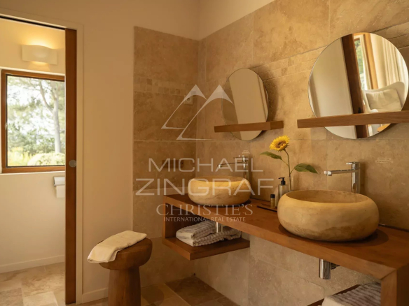 Salle de bain moderne avec lavabo en pierre et miroir rond, lumière naturelle