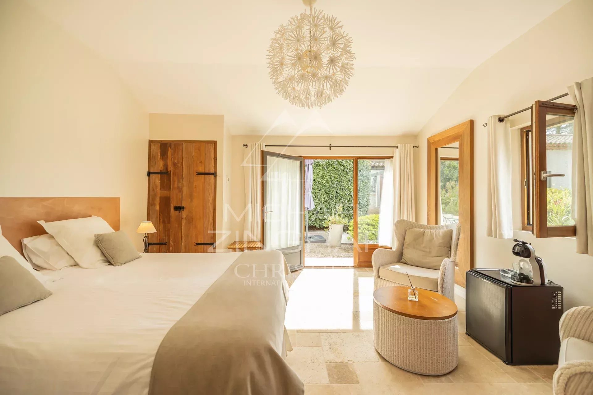 Chambre d’hôte dans une propriété rénovée à Puget Chambre lumineuse avec lit double, fauteuil et accès à un espace extérieur.