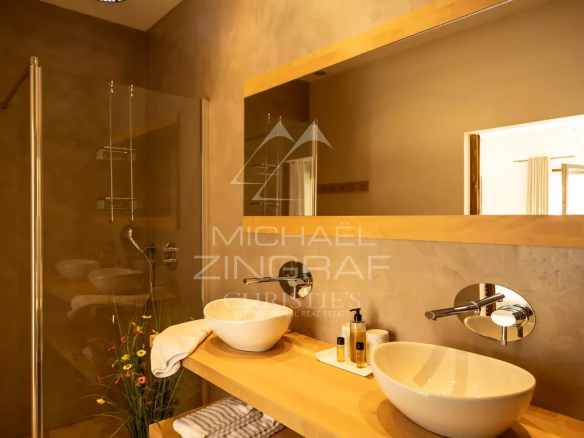 Salle de bain moderne avec douche, vasques et miroir, ambiance chaleureuse.