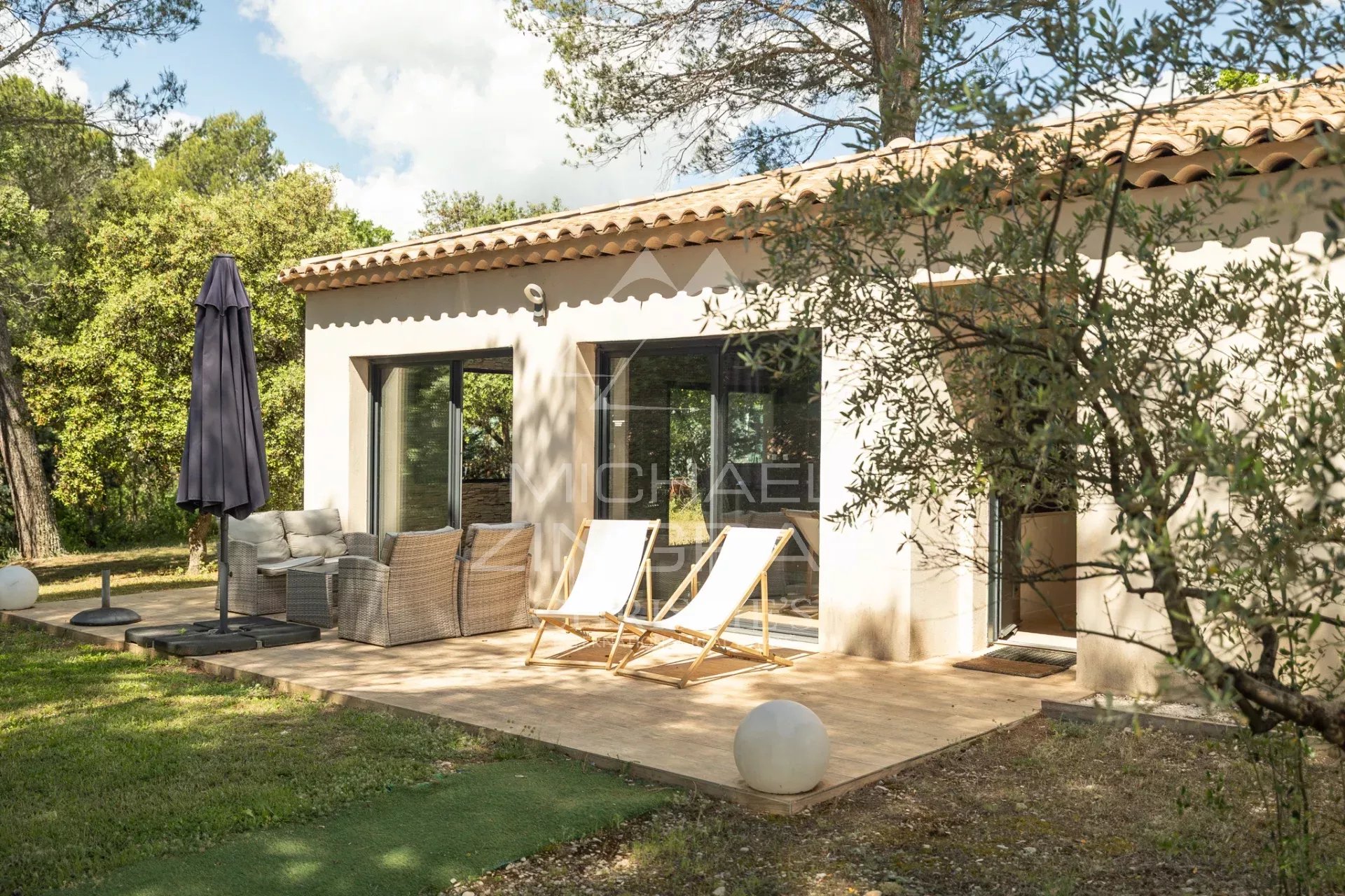 Terrasse de la propriété à Puget Terrasse d'une propriété rénovée avec chaises longues et parasol, entourée de verdure.