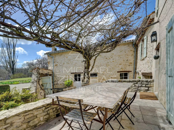 Terrace of a renovated mill with table and chairs, surrounded by greenery in Forcalquier.